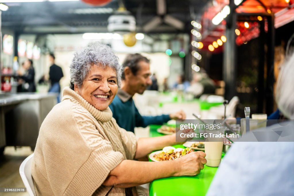 Portrait of senior woman eating with friends on a restaurant