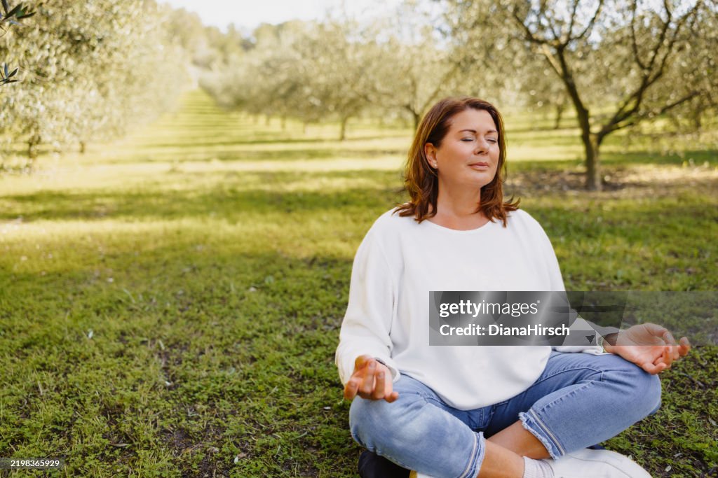Mature woman in her menopausal years sitting in Padmasana embracing stillness with her hands resting in Gyan Mudra