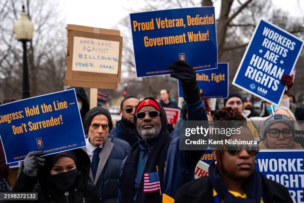 People hold signs as they gather for a "Save the Civil Service" rally hosted by the American Federation of Government Employees outside the U.S....