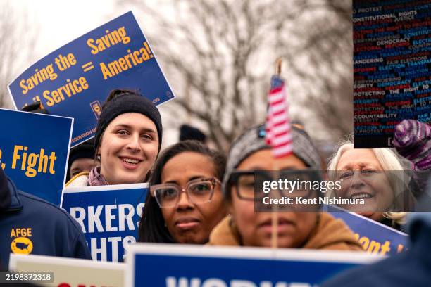 People hold signs as they gather for a "Save the Civil Service" rally hosted by the American Federation of Government Employees outside the U.S....