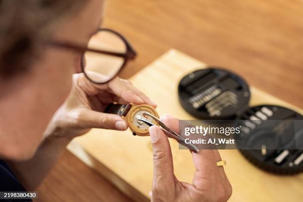 female watchmaker fixing a wristwatch in her workshop - clockwork stock pictures, royalty-free photos & images