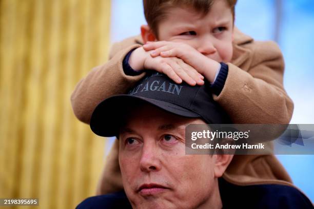Musk sits on the shoulders of his father, Tesla and SpaceX CEO Elon Musk, as they join U.S. President Donald Trump for an executive order signing in...