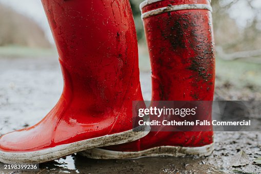 Close-up of a child wearing bright red waterproof wellington boots on a wet day Close-up of a child wearing bright red waterproof wellington boots on a wet day