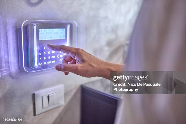 close-up of hand operating a home security system - alarma de seguridad fotografías e imágenes de stock