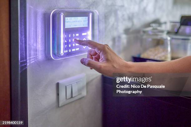 close-up of hand operating a home security system - burglar alarm stock pictures, royalty-free photos & images