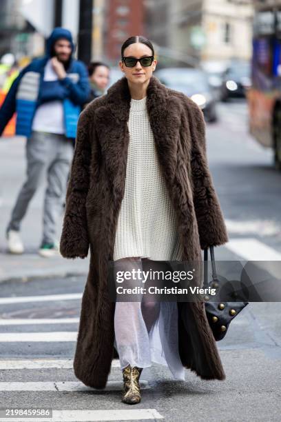 Charlotte Groeneveld wears brown fur coat, beige knit, black bag, white laced skirt outside Altuzarra during New York Fashion Week on February 08,...