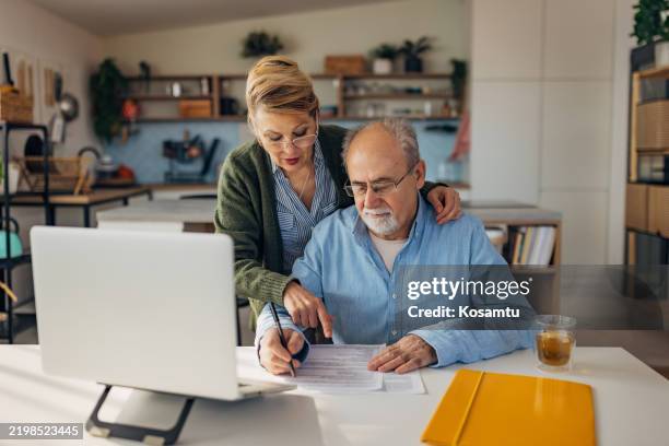a senior couple focuses on adding up their expenses and allocating their pension and income for the whole month - legal document stock pictures, royalty-free photos & images