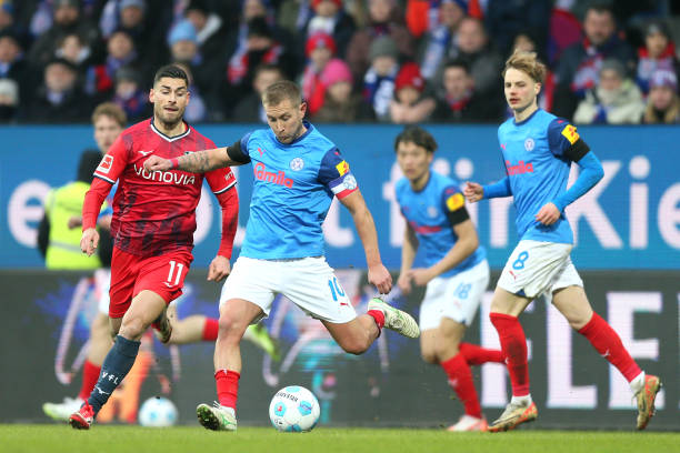 Lewis Holtby of Holstein Kiel takes a shot under pressure from Giorgos Masouras of VfL Bochum during the Bundesliga match between Holstein Kiel and...