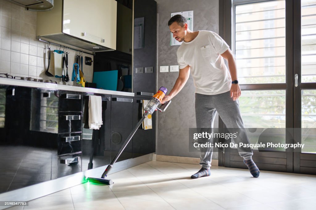 Man vacuuming floor with a cordless vacuum cleaner