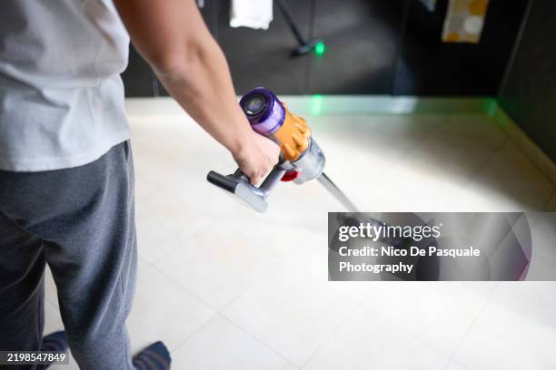 man vacuuming floor with a cordless vacuum cleaner - quarto arrumado imagens e fotografias de stock