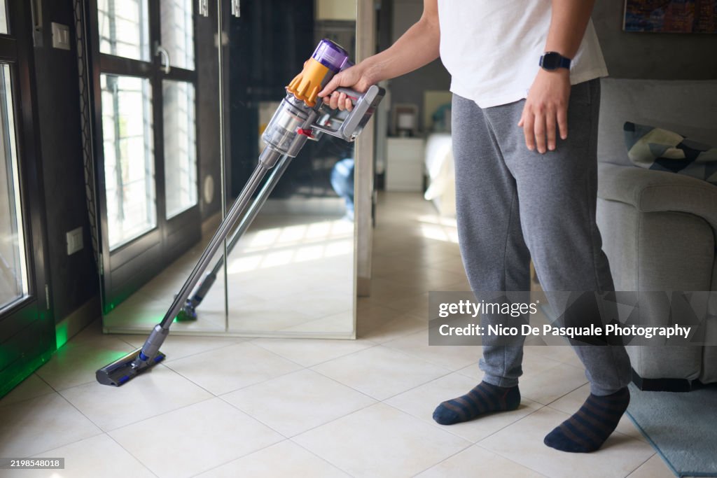 Man vacuuming floor with a cordless vacuum cleaner