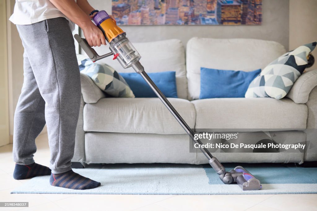 Man cleaning a rug with a cordless vacuum cleaner