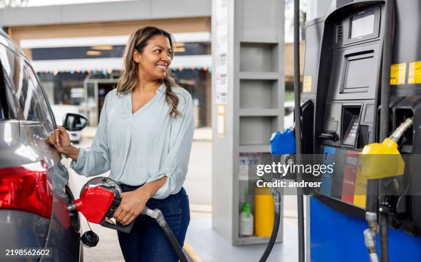 happy woman refueling her car at a gas station - fuel pump stock pictures, royalty-free photos & images