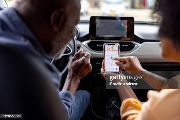 pareja de ancianos que usa su aplicación gps para planificar su viaje en automóvil - sistema de posicionamiento global fotografías e imágenes de stock