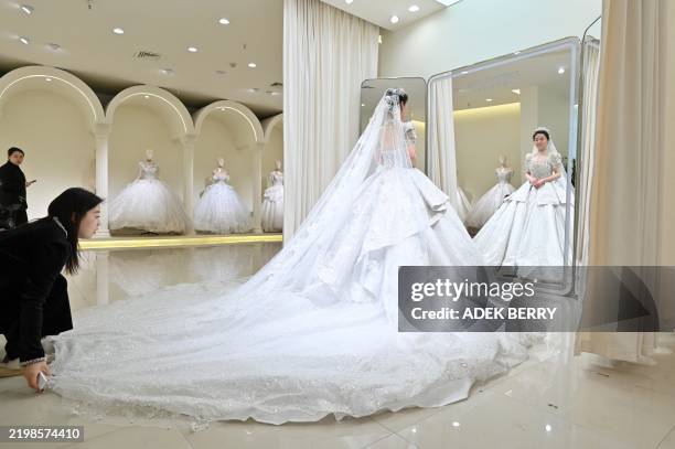 Woman fits her wedding dress at a bridal shop in Luliang, northern China's Shanxi province on February 11, 2025. Luliang in northern Shanxi province...