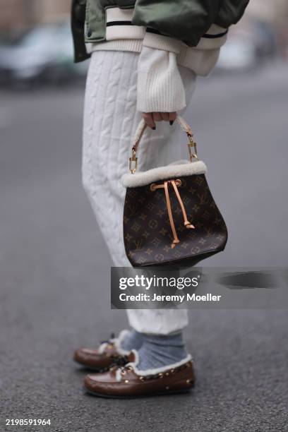 Sonia Lyson is seen wearing a shiny sage green bomber jacket from Worst behavior x Borchardt; a white knit turtleneck from COS underneath;...