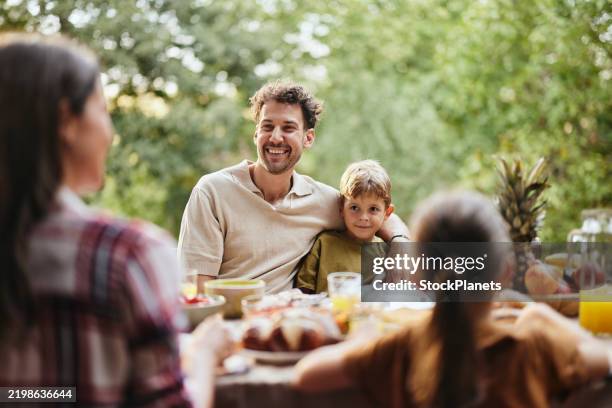 happy father and son talking to their family during a meal in nature. - trädgård bildbanksfoton och bilder