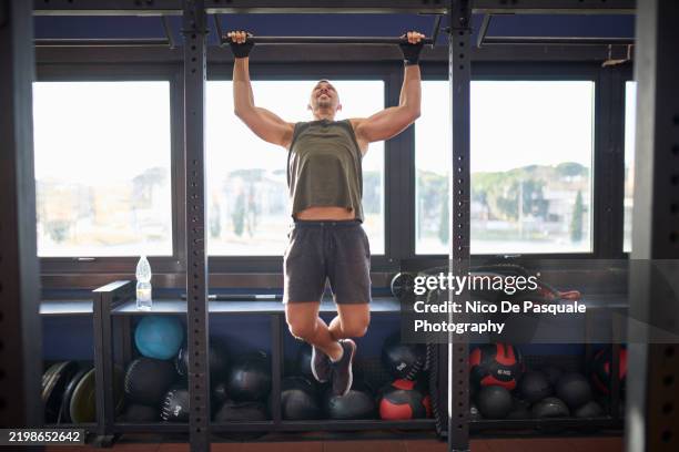man performing pull-ups in a gym - pull ups - fotografias e filmes do acervo