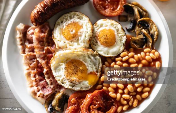 homemade full english breakast with eggs sausage ham tomato mushrooms and beans - englische kultur stock-fotos und bilder
