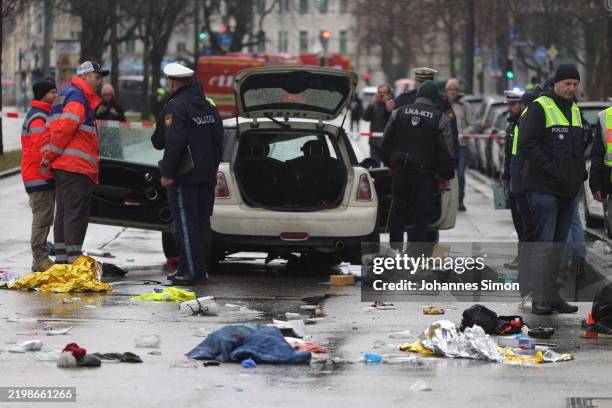 Police and emergency services operate near a damaged car that drove into demonstrators marching in the city center on February 13, 2025 in Munich,...