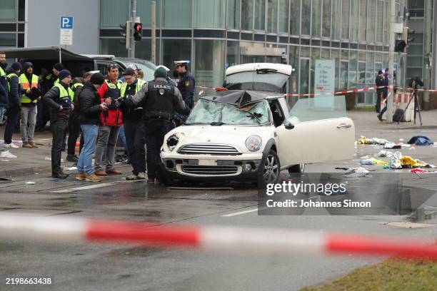 Police and emergency services operate near a damaged car that drove into demonstrators marching in the city center on February 13, 2025 in Munich,...