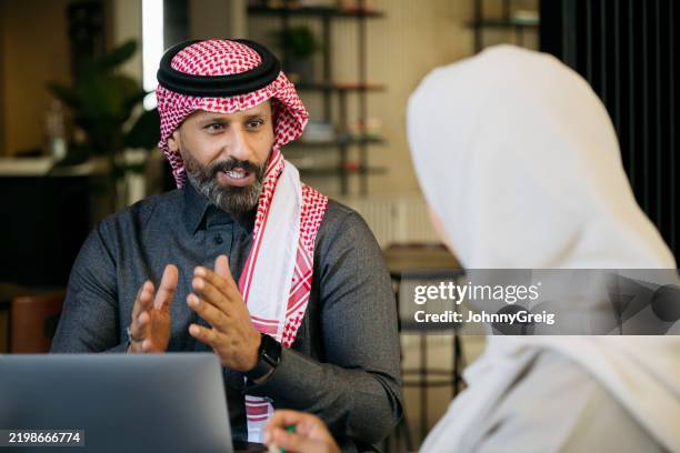 homme d’affaires arabe mature portant un keffieh parlant à une collègue féminine et gesticulant avec les mains - culture saoudienne photos et images de collection