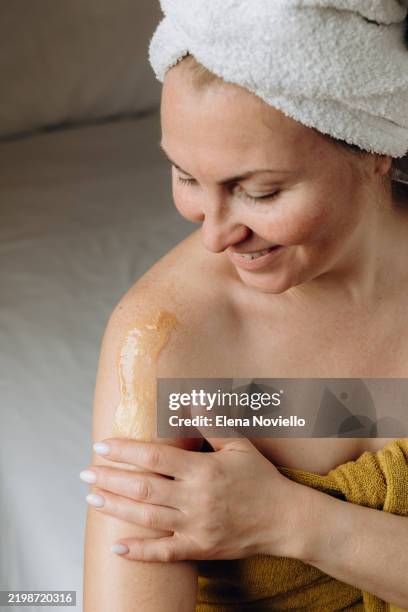 a woman applies an anti-aging cream to her skin , daily skincare and body care . the texture of a golden smear of cream balm o lotion on the skin - human skin particles stock pictures, royalty-free photos & images