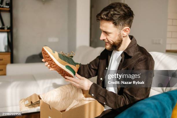 man unboxing new shoes from online purchase at home - express delivery stock pictures, royalty-free photos & images