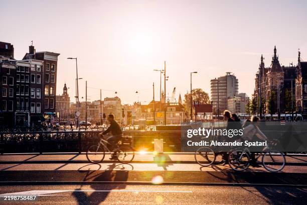 silhouettes of people riding bicycles at sunset in amsterdam, netherlands - culture néerlandaise photos et images de collection