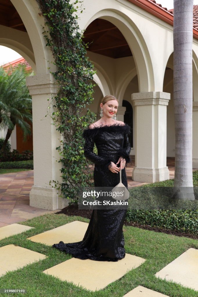 Young beautiful woman in gorgeous black formal evening gala dress with sparky purse