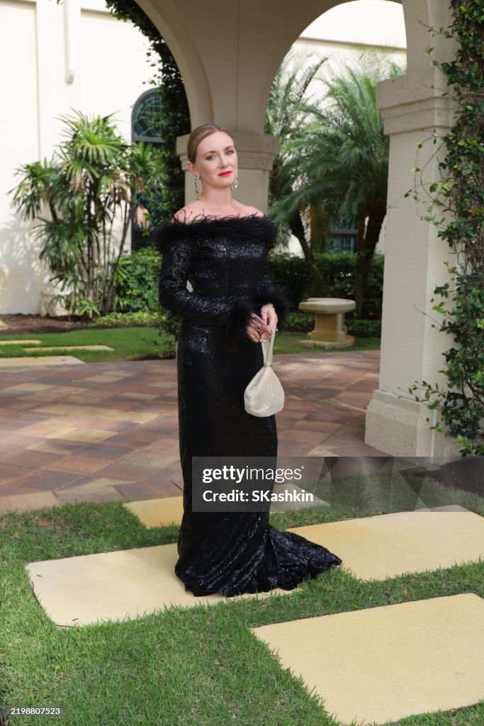 Young beautiful woman in gorgeous black formal evening gala dress with sparky purse