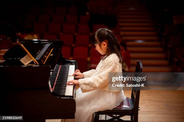 little girl playing the piano in concert hall - side view - pianist stockfoto's en -beelden