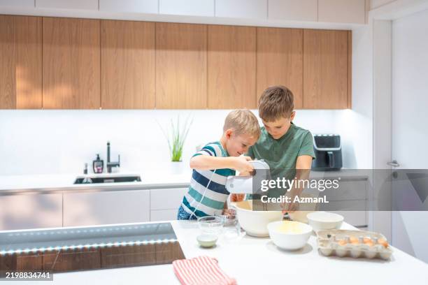 joyful caucasian brothers baking together in modern kitchen - electric mixer stock pictures, royalty-free photos & images