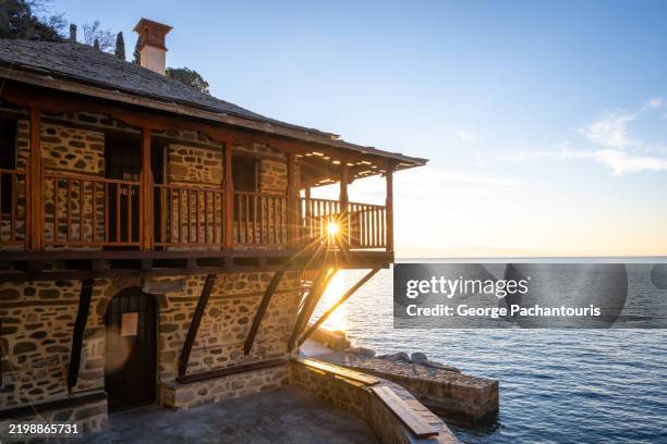 sunset at rustic seaside stone building on mount athos, greece - casa al mare foto e immagini stock