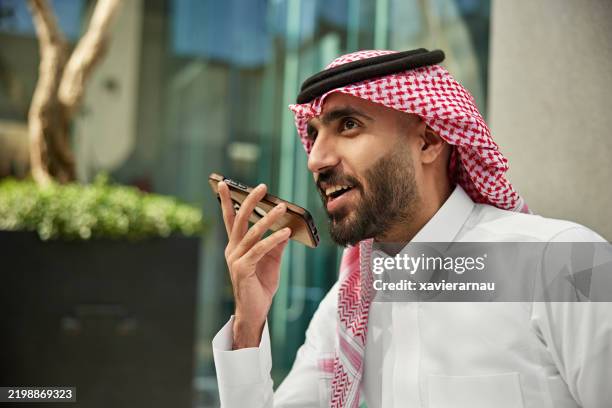 jeune professionnel saoudien utilisant son téléphone à l’extérieur - culture saoudienne photos et images de collection