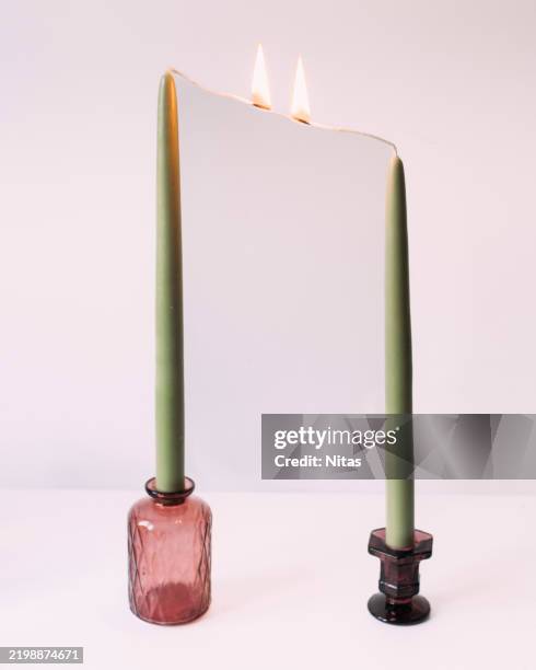 two green candles burning with reflecting mirror effect on white background - candlestick holder stock pictures, royalty-free photos & images