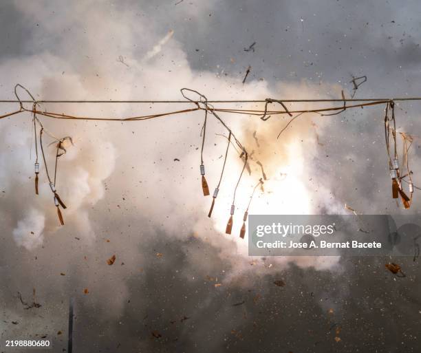 pyrotechnic show called "mascleta", large explosions of firecrackers and rockets during a daytime fireworks display. - petardo fotografías e imágenes de stock