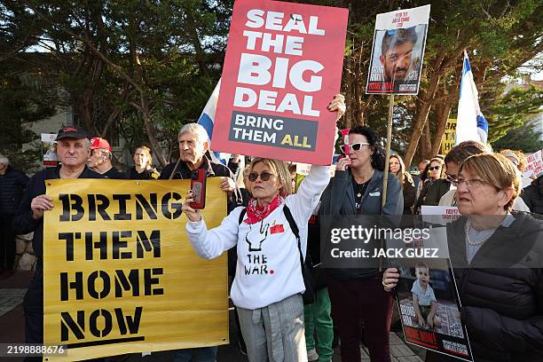Demonstrators raise placards and chant slogans during a protest calling for the release of hostages held captive in Gaza since the October 7, 2024...