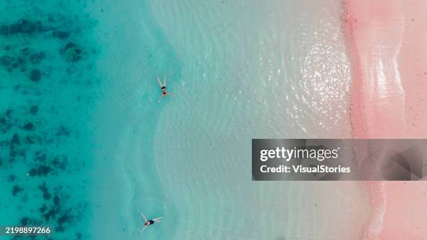 aerial view of two women in turquoise ocean at pink beach - pink lagoon stock pictures, royalty-free photos & images