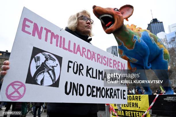 Participant displays a placard reading 'De-billionaire-ize for climate, nature and democracy' during a 'Fridays for Future' demonstration as part of...
