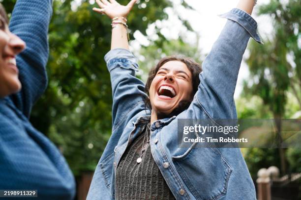 two women with arms in the air, happy, playful - boa notícia imagens e fotografias de stock