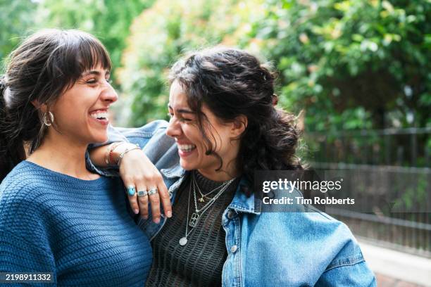 woman smiling and leaning on her freinds shoulder - friends stock pictures, royalty-free photos & images