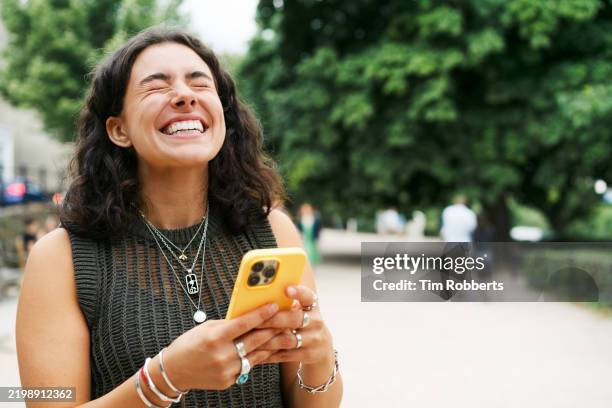 woman laughing whilst using smart phone - euforia foto e immagini stock