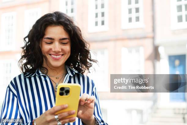 woman using smart phone on street - striped shirt stock pictures, royalty-free photos & images