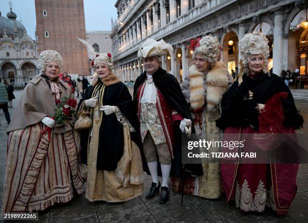 Revellers wearing period costumes pose during the traditional Venice Carnival, starting today on February 14, 2025. This year, the theme of one of...