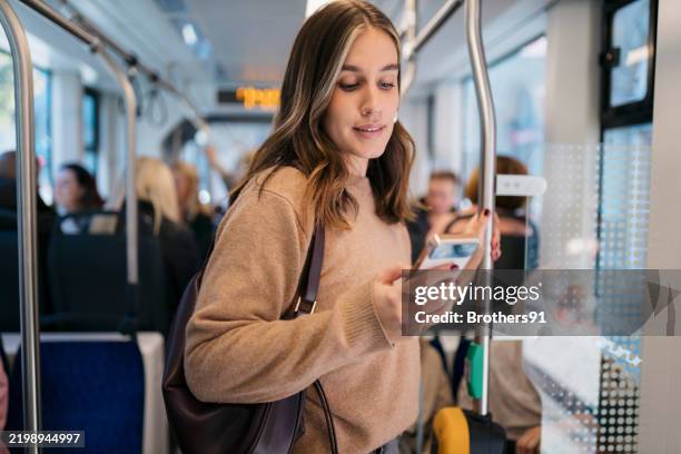 young woman using smartphone while standing on public transport - a caminho imagens e fotografias de stock