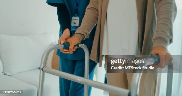 nahaufnahme einer jungen asiatischen krankenschwester hilft einer älteren frau, einen rollator zu benutzen mobilitätshilfe im wohnzimmer zu hause. häusliche krankenpflege. - ambulante behandlung stock-fotos und bilder