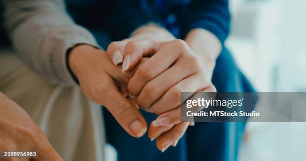close-up of young asian nurse comforts an elderly woman on a sofa, emotional support and care in living room at home. home health care. - hospice stock pictures, royalty-free photos & images