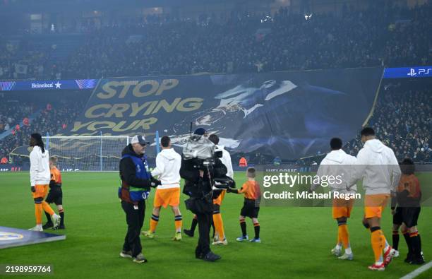 Fans of Manchester City display a tifo which reads 'Stop crying your heart out' which includes a picture of Rodri of Manchester City kissing the...
