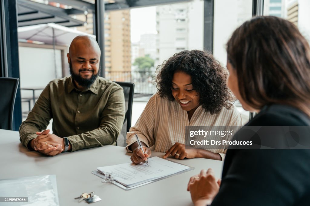 Couple closing real estate contract with real estate agent